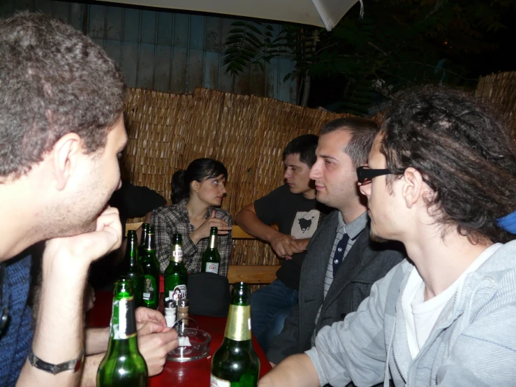 a group of people at a bar with several bottles of beer