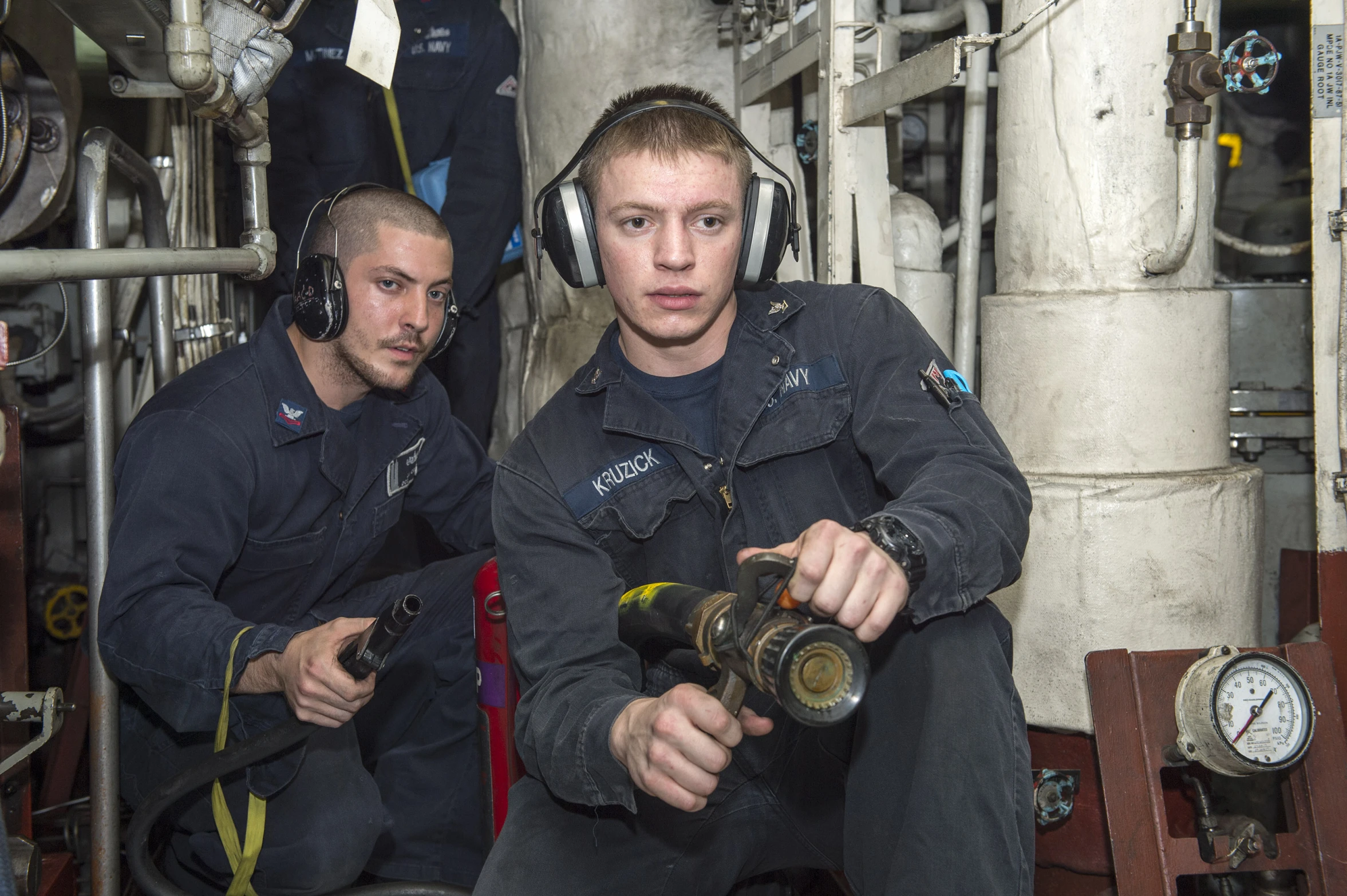 two men sitting on a ship working with machinery