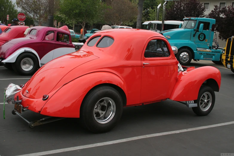 an old style red car parked in a parking lot