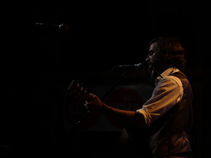 a man standing at a microphone while holding a guitar