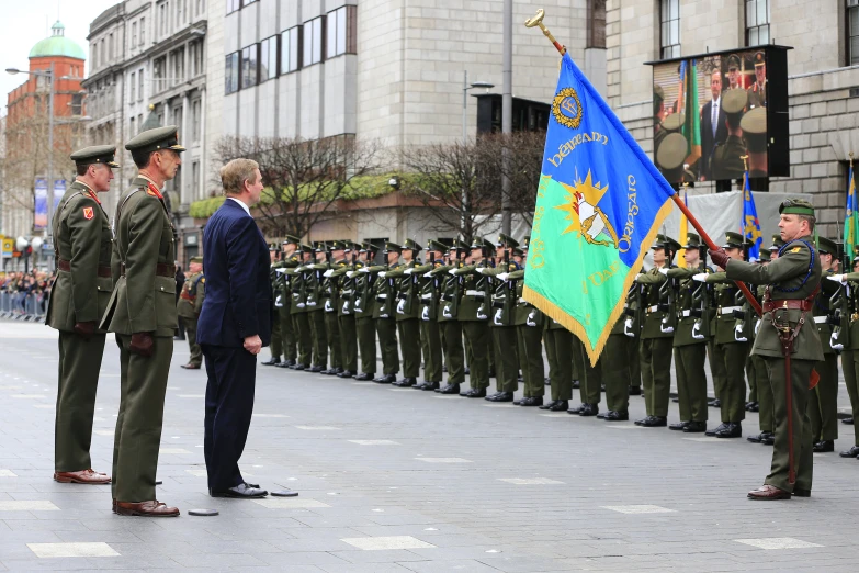 two men in military uniforms are saluting for some soldiers