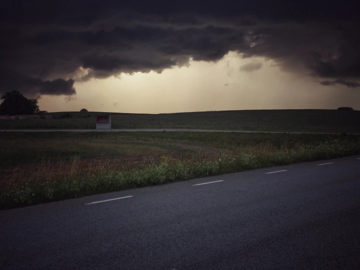 dark clouds loom over a green field in the evening