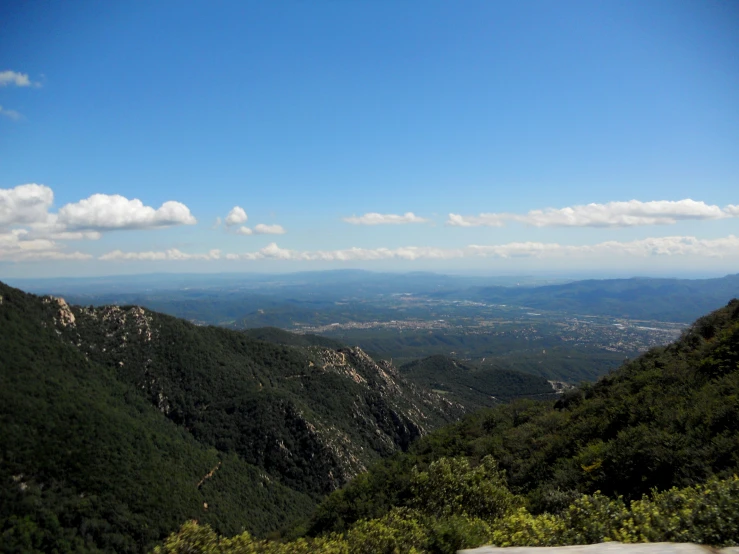 a mountain scene has green trees and the sky