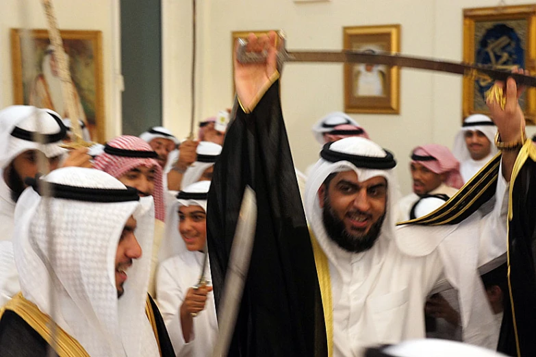 a group of men standing in a building with their arms up in the air