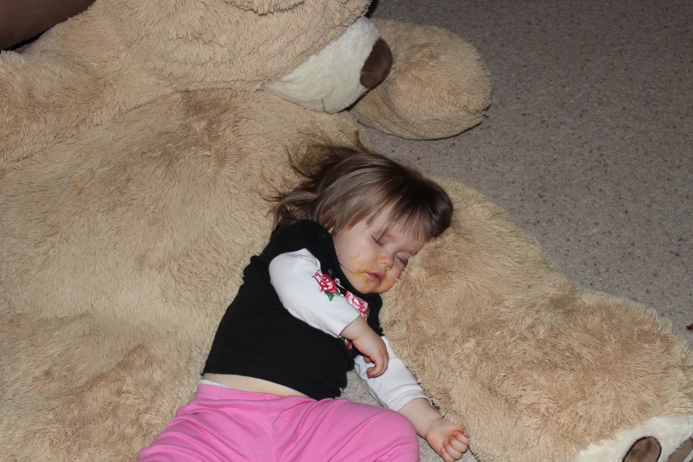 a small child is laying next to a giant teddy bear