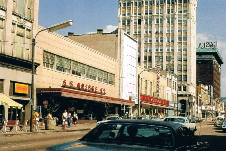 a car is driving down a city street with tall buildings