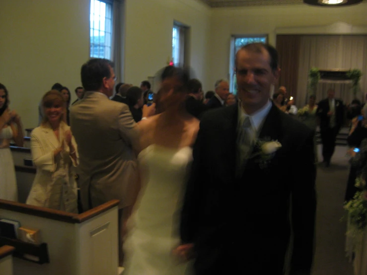 a man and woman in formal clothing walk through the church