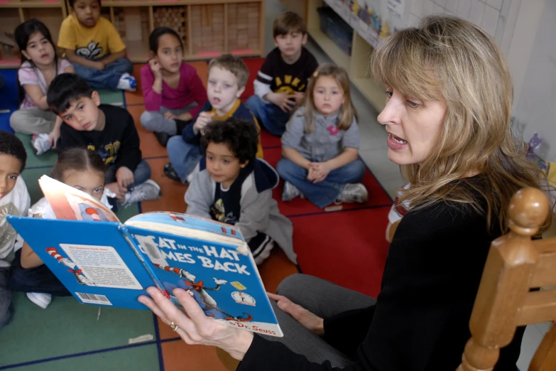 a woman reads a story to children in the classroom