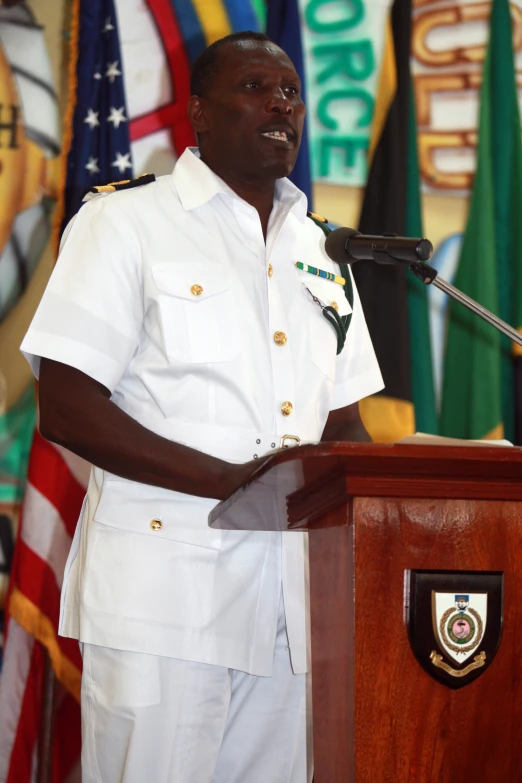 a man wearing a white uniform standing behind a podium