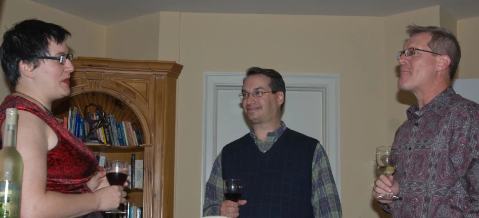 a man standing in a room next to two women holding wine glasses