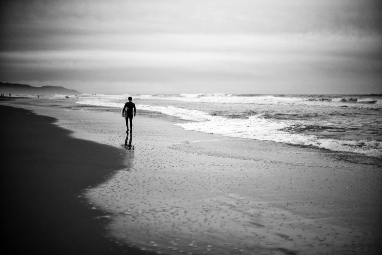 a person stands on a beach as the tide rolls in