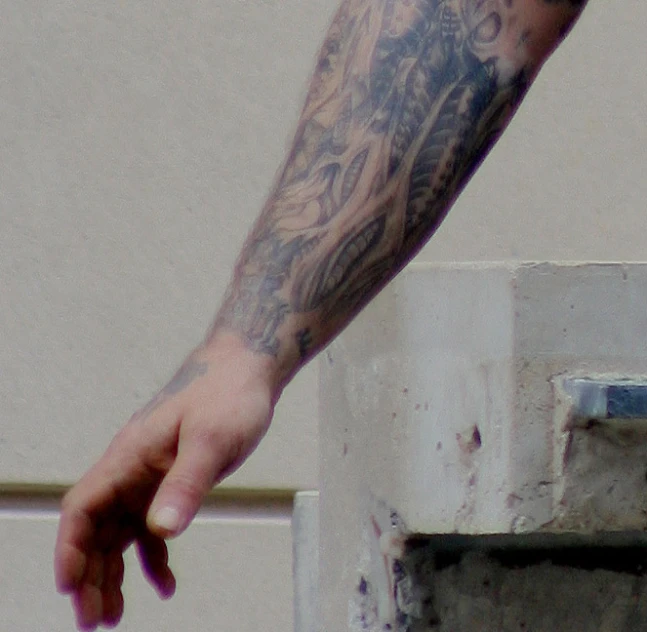 arm and arm with tattoos is outside near some windows