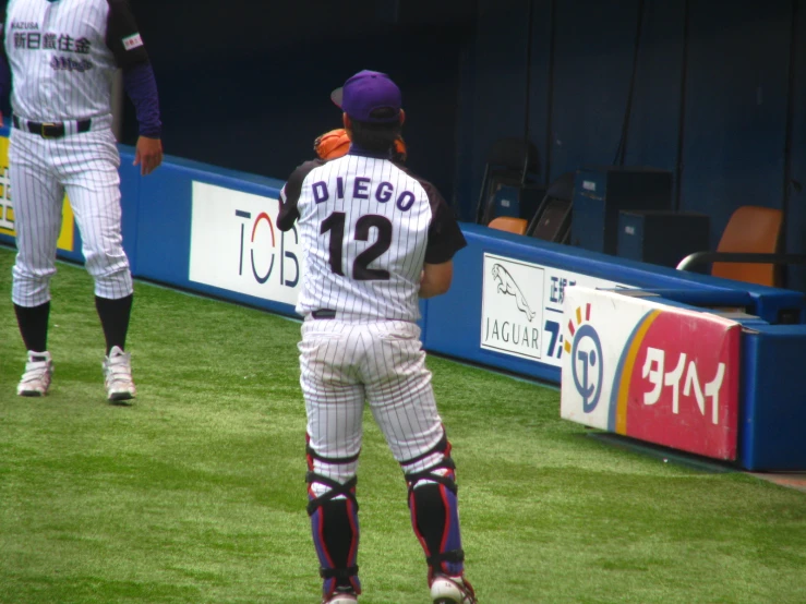 baseball player in white and black uniform standing at dugout