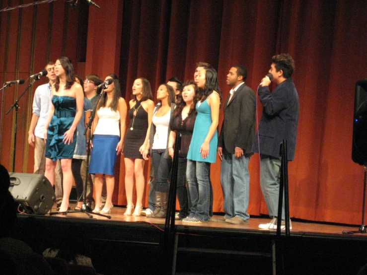 a group of young people stand on a stage to sing a song