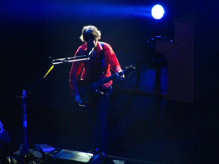 a person playing a guitar and singing into microphones