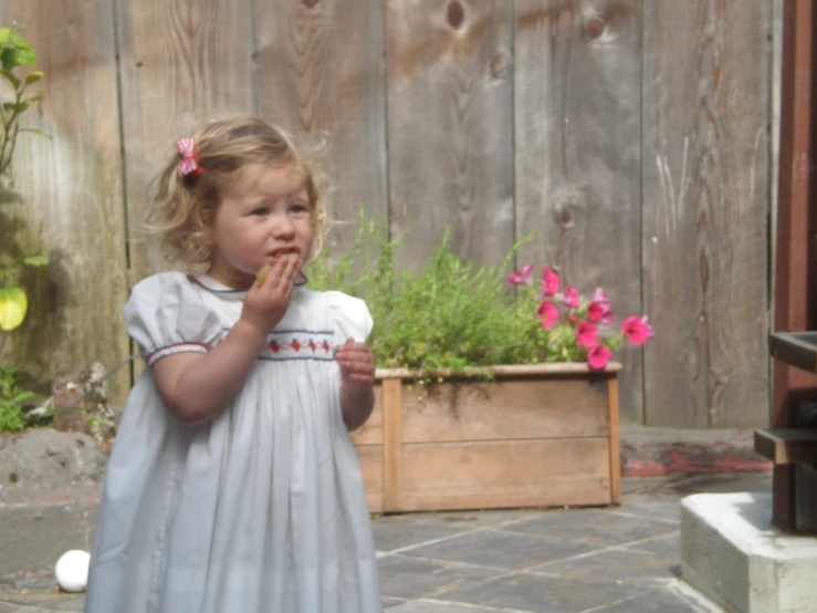 a small girl stands near flowers and plants