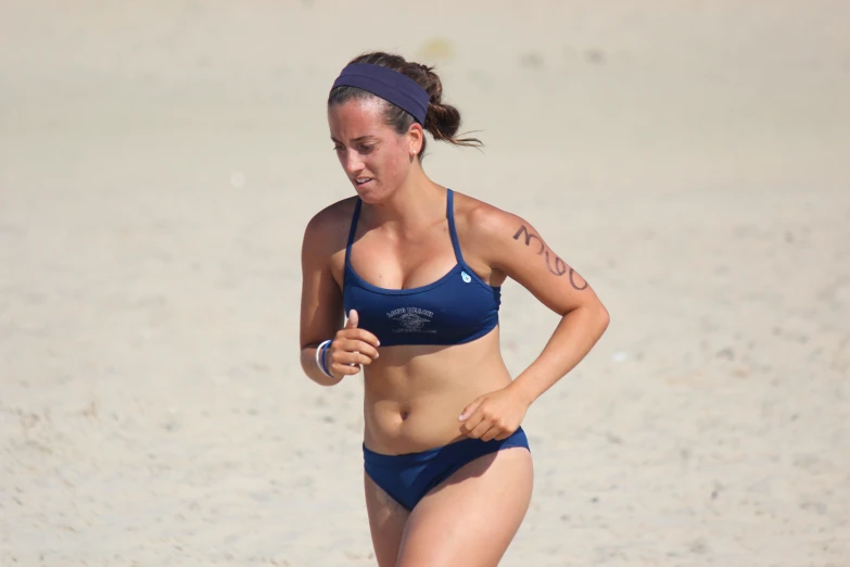 a woman standing on the beach with tattoos