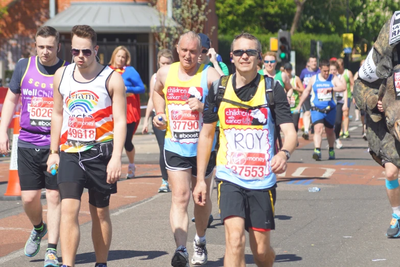 people walking through the street, wearing running bibs