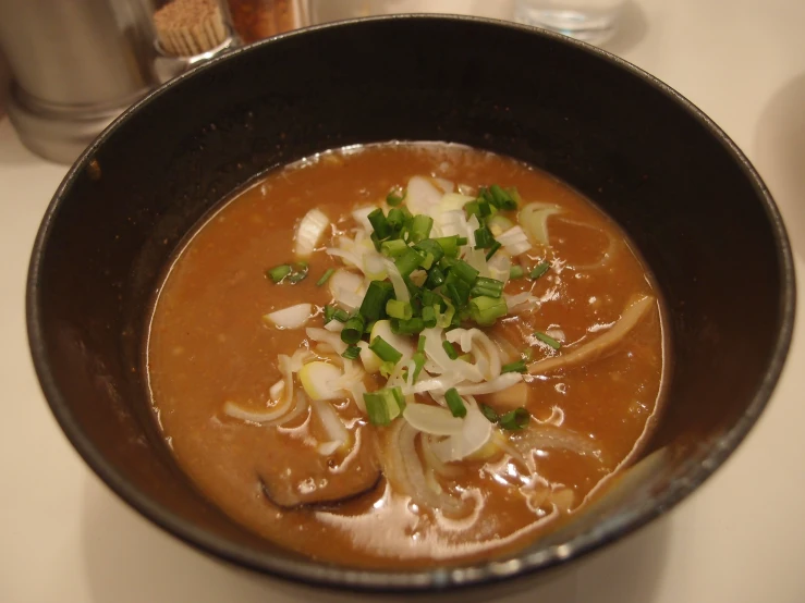 a bowl on a table containing soup and vegetables