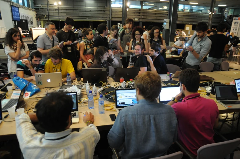 a group of people sitting around table with laptops