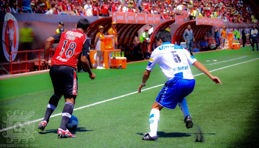 three soccer players are going after the ball in a match