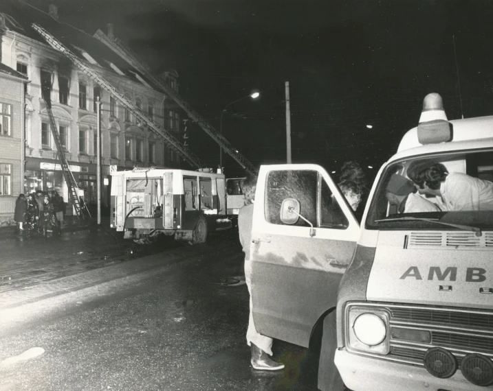 black and white po of a man standing next to a police car