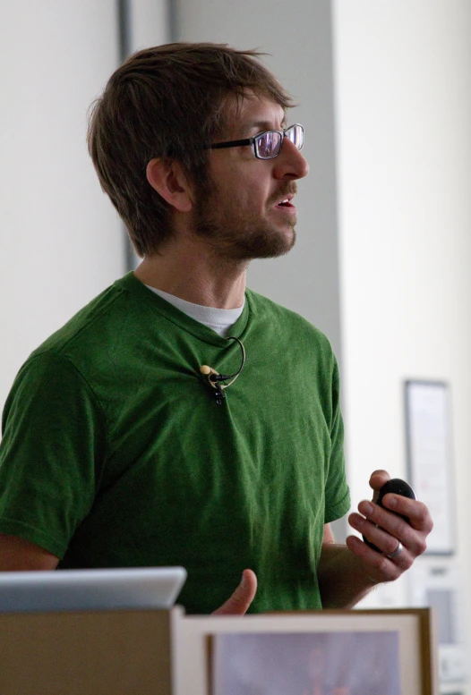 a man in a green shirt speaking at a podium