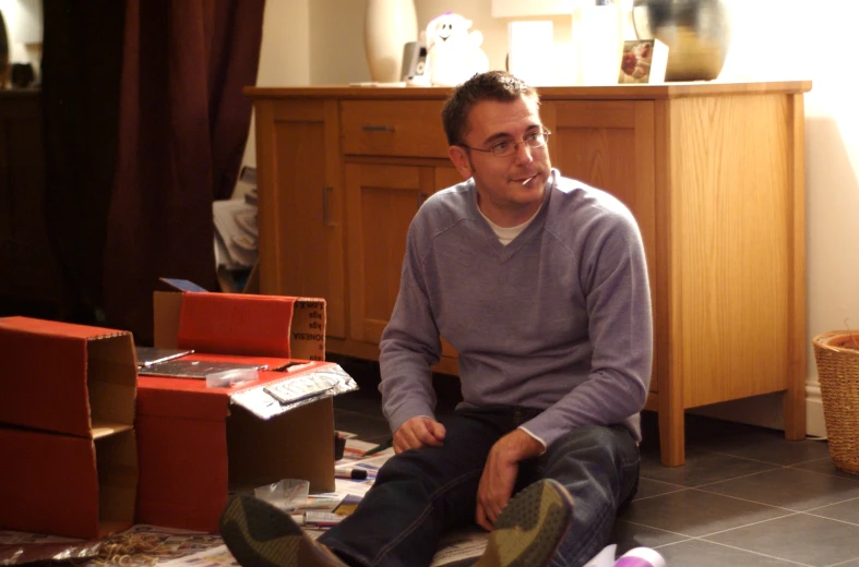 a man is sitting on the floor in a cluttered living room