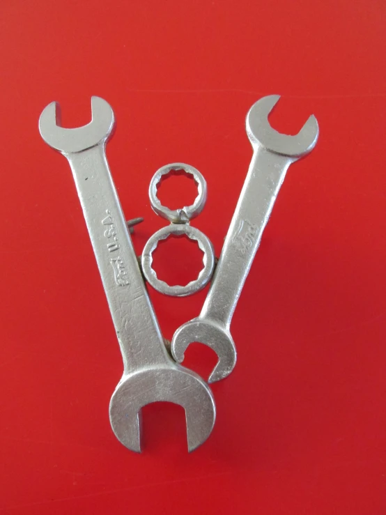 two wrenches and a pair of keys on a red surface