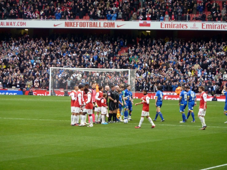 several men playing a game of soccer as a crowd looks on