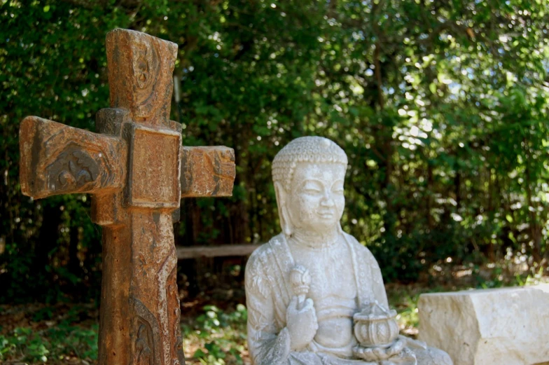 there is a cross and a stone statue in the grass