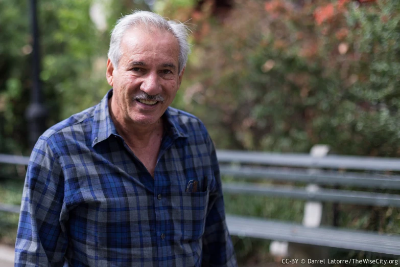 a man wearing plaid shirt smiling for a po