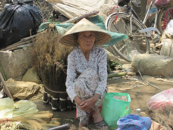 a woman wearing a big hat sitting on the ground