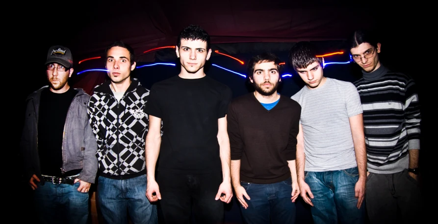 six men standing together on the street at night