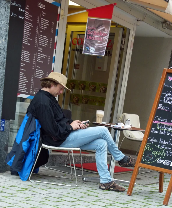 a person is sitting at a table outside in front of a cafe