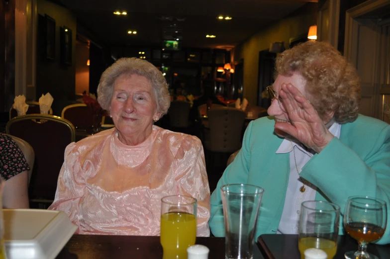 two women sitting at a table with drinks