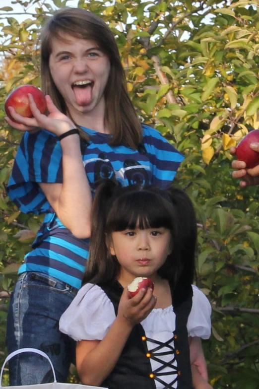 two little girls standing by an apple tree