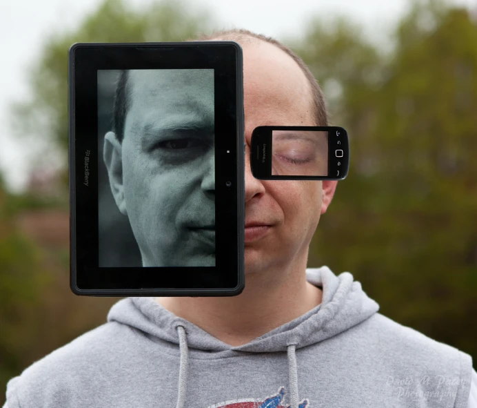 a man holding up a smartphone with a picture on it's back
