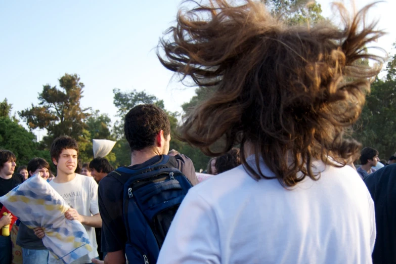 a young man has his hair blowing in the wind as another guy looks