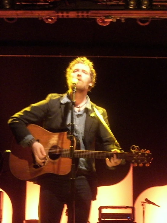 a man with a guitar on stage in a dark room