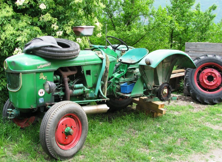 an old tractor with big tires parked in front of a barn