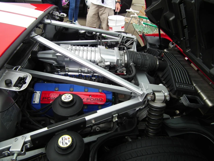 the engine compartment in a car with people standing around it