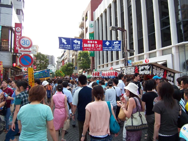 a group of people walking down a street with shops on each side