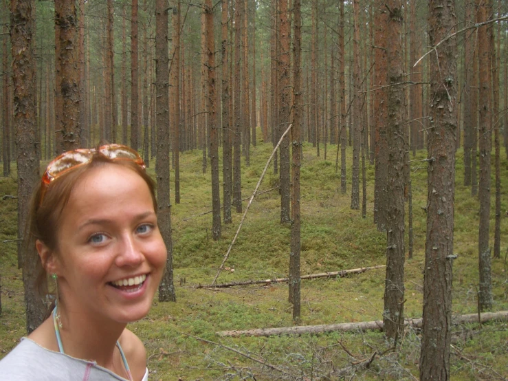 a woman smiles in the forest while wearing a bandana
