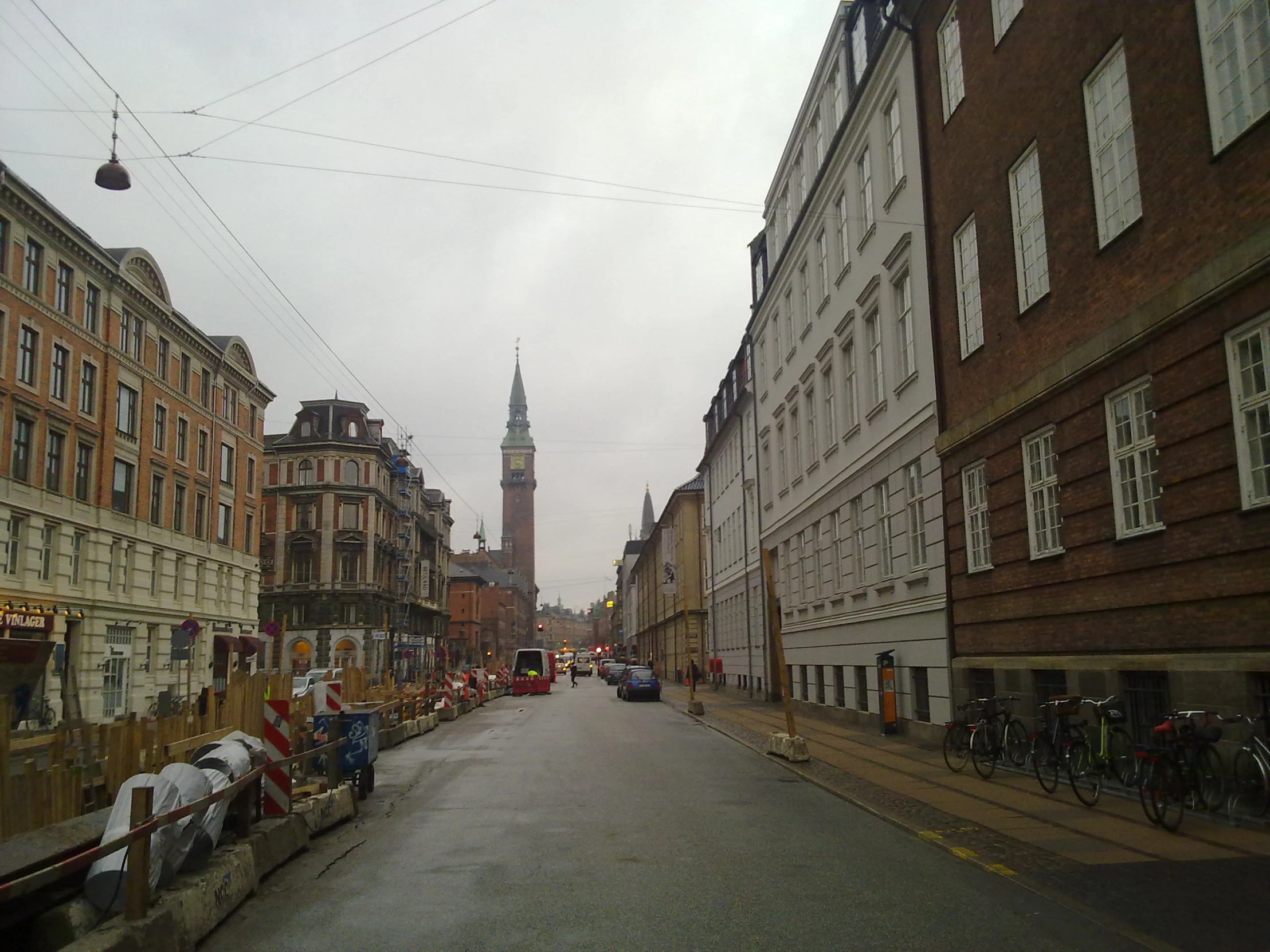 a city street with traffic and a tall steeple