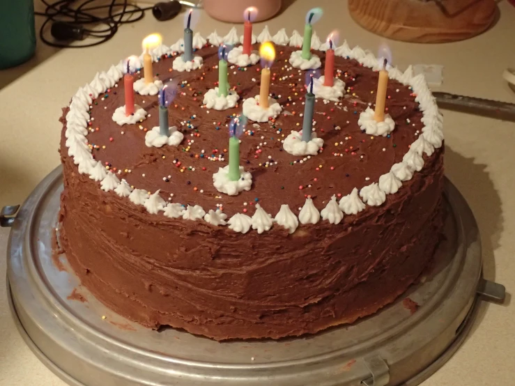 a chocolate cake with candles on top and one candle lit