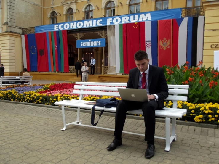 a man wearing a suit and tie sitting on a bench