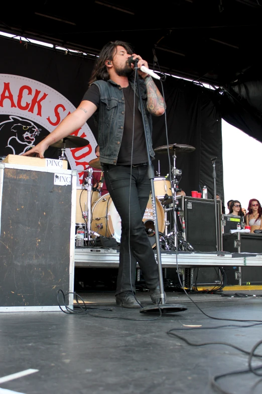 a man with long hair and  standing on a stage holding a microphone