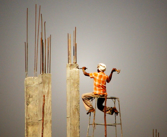 a man on a ladder working next to two concrete columns