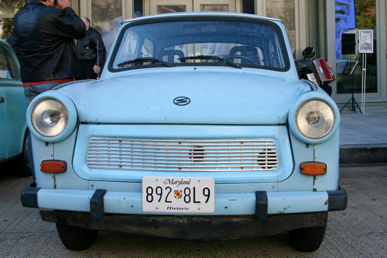 an old blue car parked on the side of the road